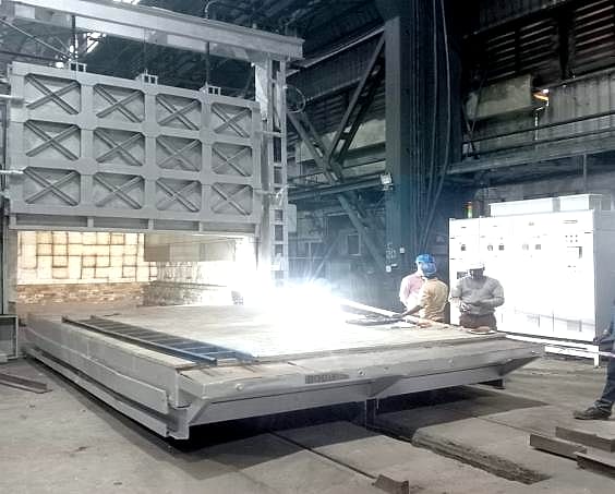Bogie hearth furnace with its hearth car pulled out, technicians welding on site